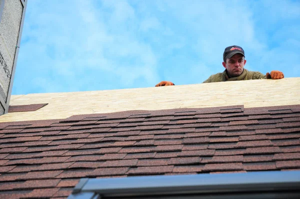 Telhados que colocam telhas de asfalto no telhado da casa. Roofer com corda de proteção, kit de segurança no telhado da casa de instalação superior, telhas de asfalto de reparação. Construção de telhados — Fotografia de Stock