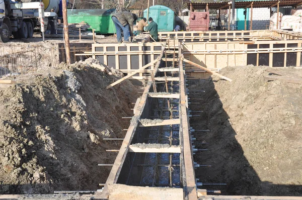 Contratistas constructores que instalan el marco de hierro y madera para construir una construcción de cimentación de la casa ubre. Construcción de cimientos de casa incompleta . —  Fotos de Stock