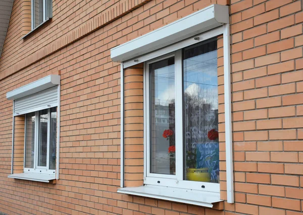 롤링 셔터는 창문 보호 기능을 수용합니다. 창문에 금속 롤러 셔터가있는 벽돌 집 — 스톡 사진