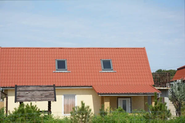 Casa rural com telhado de metal vermelho e janelas sótão clarabóia — Fotografia de Stock