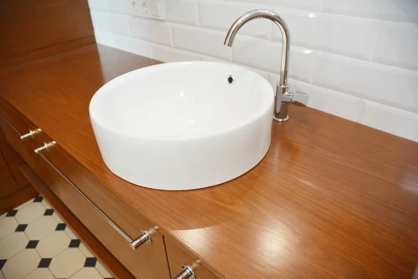 Lavabo de cerámica de baño con grifo de agua y mesa de madera . —  Fotos de Stock