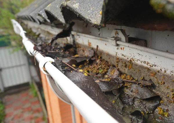 Regengoot reiniging van bladeren en vuil. Reinigings tips voor de afvoer van dakgoten. Reinig de dakgoten voordat ze uw portemonnee opruimen. Guttering werkt. — Stockfoto