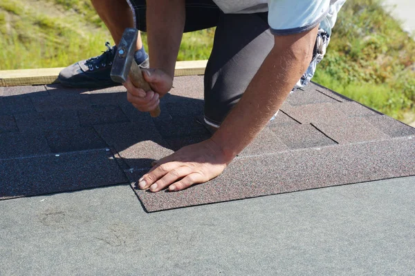 Roofer riparazione, ristrutturazione, installazione di tegole di asfalto sulla costruzione di tetti di casa con martello e chiodi in azione. Riparazione tetti, ristrutturazione tetti — Foto Stock