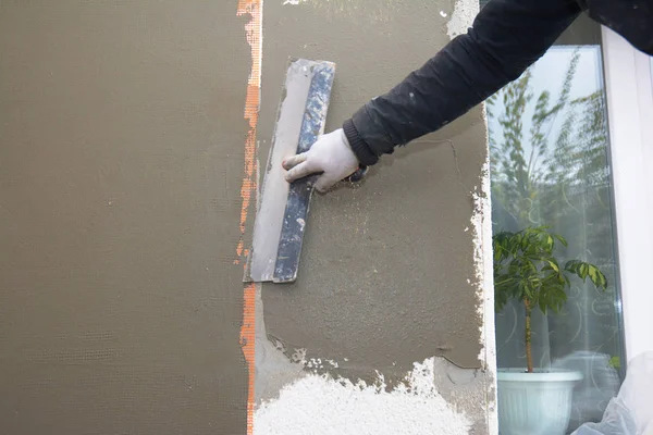 Renovación de la pared de la casa, insualción con capas de enlucido, malla de refuerzo, aislamiento de espuma de poliestireno, acabado de renderizado, estuco. Mano del contratista con paleta que hace aislamiento externo de la espuma de pared — Foto de Stock