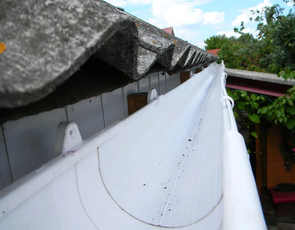 Close up on rain gutter pipeline on house rooftop with asbestos roof. — Stock Photo, Image