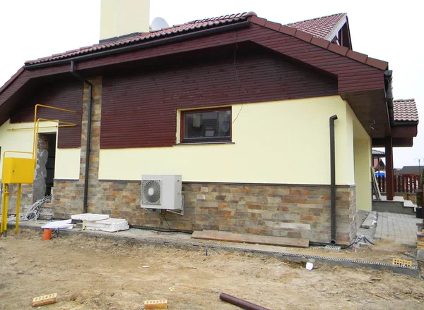 Fachada de la casa en construcción con canaleta de lluvia tubería descendente, pared de cimentación de la casa, conducto de aire — Foto de Stock