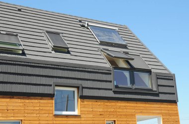 Tavan penceresi pencereleri, güneş enerjili su ısıtıcısı, güneş panelleri, asfalt zona ile modern pasif ev çatı.