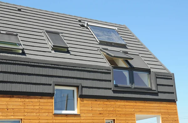 Современная пассивная крыша с окнами на чердаке, солнечный водонагреватель, солнечные батареи, асфальтовая черепица . — стоковое фото