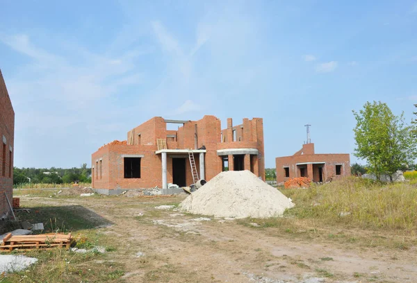 Construcción de casa de ladrillo incompleta con columnas de puerta y marco de ventanas, pila de arena — Foto de Stock