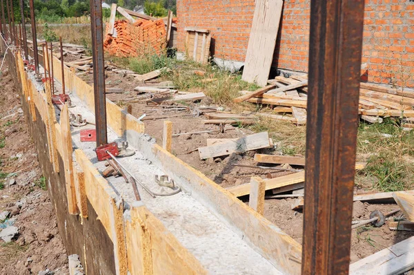 Building concrete foundation for new fence. House fence construction site during concrete pouring slabs works with formwork. — Stock Photo, Image