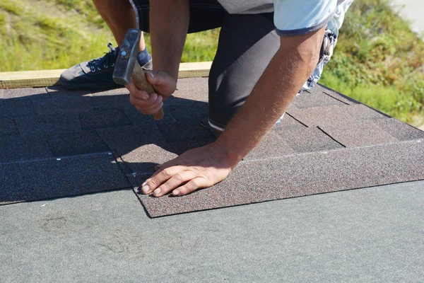 Roofer repair, renovating, installing asphalt shingles on house roofing construction with hammer and nails in action.  Roof repair, roof renovation — Stock Photo, Image