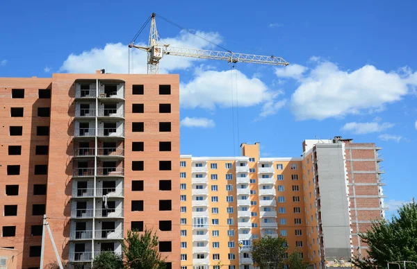 Building crane and building under construction with insulation, paiting walls and building contractors. — Stock Photo, Image