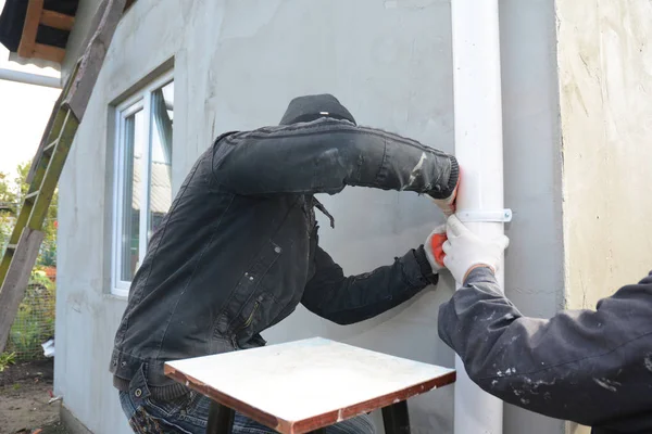 İşçiler, House Wall'da Rain Gutter Downspout Pipe, Waterspout'u kurar ve onar. Çatı drenaj borusu 