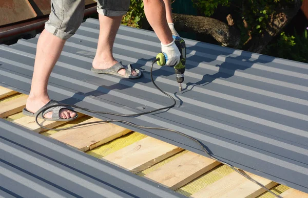 Construção de telhados. Roofer com pistola de tripulação instalando telhas de telhado de metal leve construção de telhados na construção de telhados de casa — Fotografia de Stock