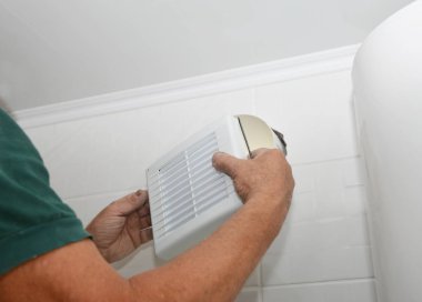 Tamirci evin banyosuna yeni havalandırma vantilatörü ve havalandırma sistemi kuruyor. Banyo vantilatörü tamiri, kurulum.