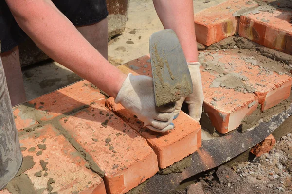 Bricklayers ręce z w murowanej kielni murarskiej muru nowego domu ściany na fundamencie. — Zdjęcie stockowe