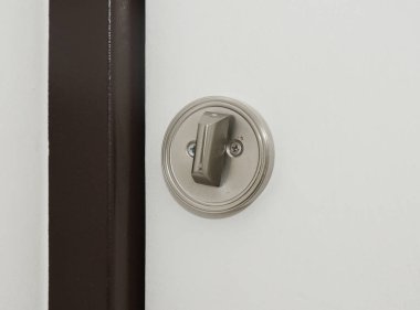 Yuvarlak floş çekiş mahremiyet kiti, sürgülü banyo kapısı kilidi olan beyaz bir kapıya yakın çekim..