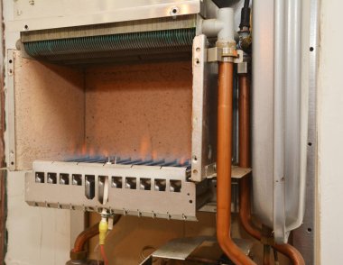 Isıtma sırasında açık gaz kazanının içindeki mavi gaz ocağı kontrol ediliyor..