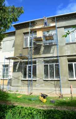Binanın dış duvarına büyük pencereler döşemek, alçı, sıva, sıva ve palto döşemek için yüksek yapı iskelesi kuruluyor.