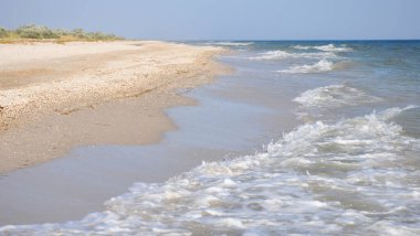 Köpük deniz dalgaları, derin mavi su ve altın kumsal ile güzel bir deniz manzarası..