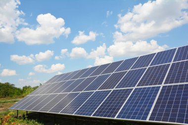 Büyük bir güneş enerjisi sistemine yakın çekim, yere monte edilmiş güneş paneli mavi gökyüzüne karşı.
