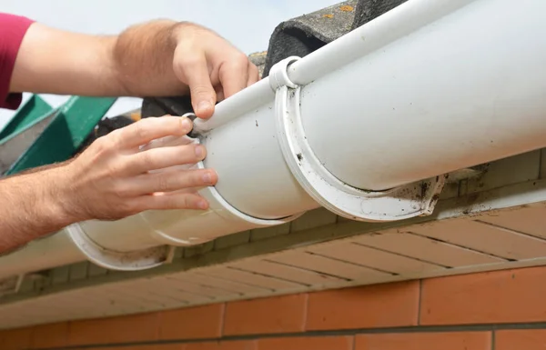 Man Installing Repairing Roof Gutter Fitting Union Bracket Screwing Fascia — Stock Photo, Image