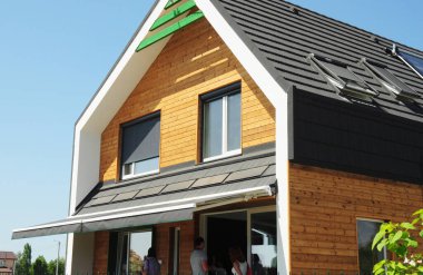 Modern enerji tasarruflu tavan pencereli ahşap ev ve asfalt kiremitli güneş paneli çatı, tekerlekli kepenkli pencereler ve açık hava tepe örtüsü geri çekilebilir çatı, veranda güneşliği. 