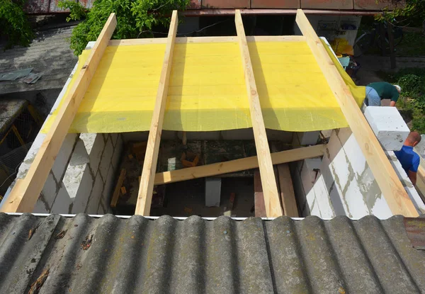 Constructing roof with trusses, roof beams, vapor barrier of home addition, home extension from autoclaved aerated concrete blocks of the house with asbestos roof.