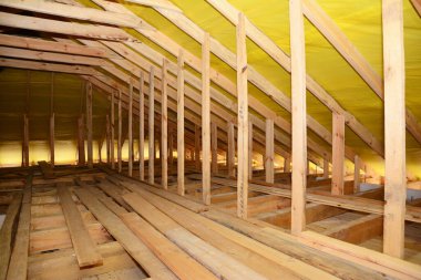Tahta kirişler, kirişler, çatı kirişleri, tavan kirişleri ve yeni bir evin içinde buhar bariyeri filmi olan bitmemiş bir tavan arası inşaatına yakın plan..