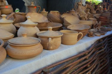 Bir ticaret fuarı sırasında farklı türde Ukrayna el yapımı kil çömlek, işlenmemiş kil kaplar, kaseler, sürahiler ve kupalar bir sokakta satılır.. 