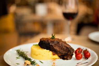 Kırmızı şarap haşlanmış dana yanakları, patates püresi ve yabanturpu, domates ile servis edilir. Menü için fotoğraf 