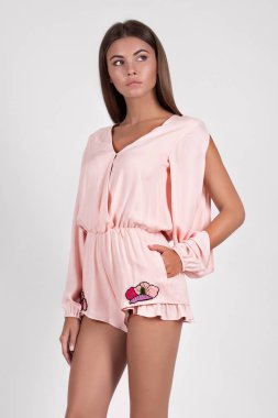 Stüdyoda pembe tulumlu güzel bir kadın poz veriyor. 