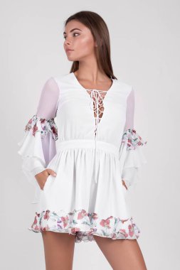 Stüdyoda poz veren, çiçekli tulum giyen güzel bir kadın. 