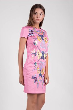 Stüdyoda poz veren, çiçekli pembe elbiseli güzel bir kadın. 