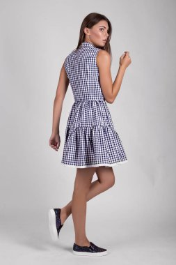 Stüdyoda mavi ekose elbise giymiş güzel esmer kız.