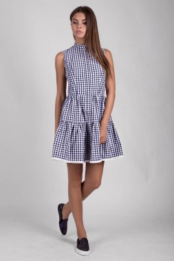 Stüdyoda mavi ekose elbise giymiş güzel esmer kız.