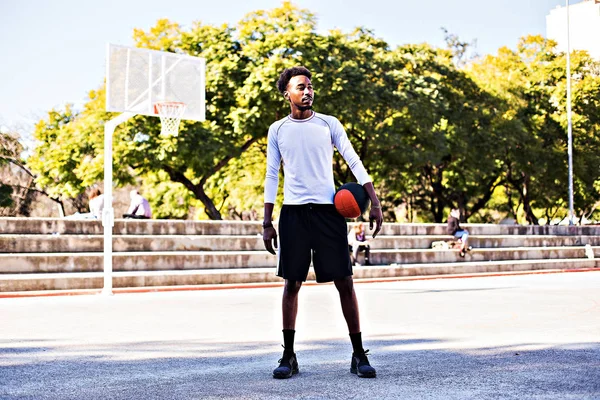 Young athletic black man posinging on court with ball, basketball game player, morning exercises, active healthy lifestyle, hot summer day, streetball.