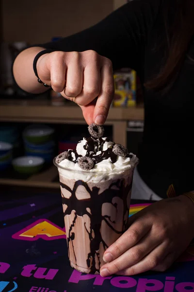 Bartender woman preparing milkshake with chocolate.