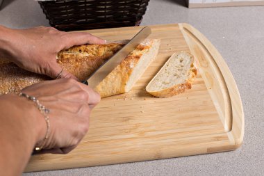 Ekmek ve bıçak ile ahşap kesme tahtası, bir kadın taze ekmek keser. 