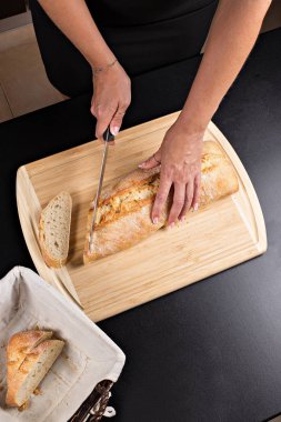 Ekmek ve bıçak ile ahşap kesme tahtası, bir kadın taze ekmek keser. 