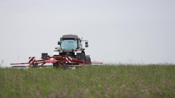 Traktor fährt mit Mähdrescher beim Grasernten auf Wirtschaftsweg — Stockvideo