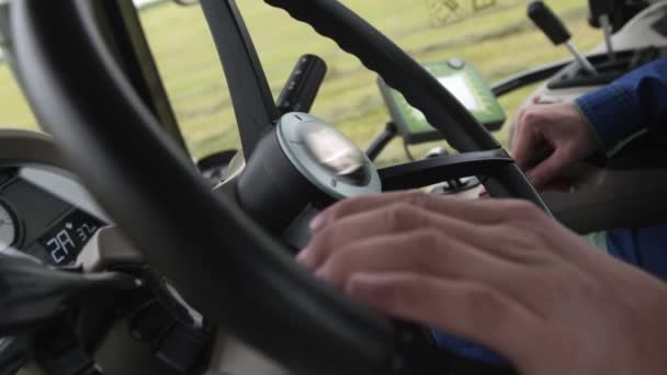 Hands of driver on steering wheel of tractor riding on farm field — Stock Video