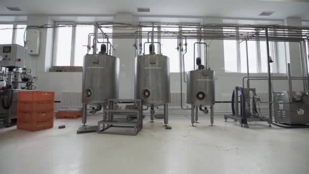 Drei Pasteurisierungstanks mit Leiter in der Fabrik. Arbeiter geht durch — Stockvideo