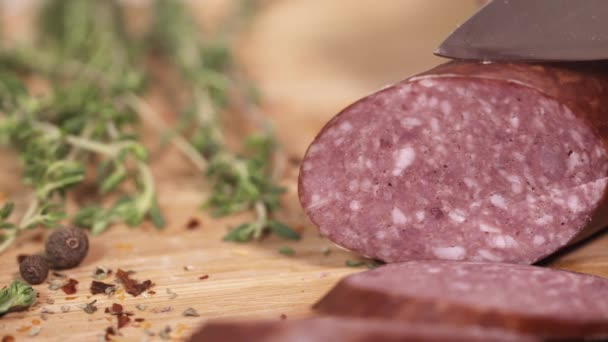 Carne fresca delicatessen sendo cortado com faca na placa de corte ao lado de ervas — Vídeo de Stock