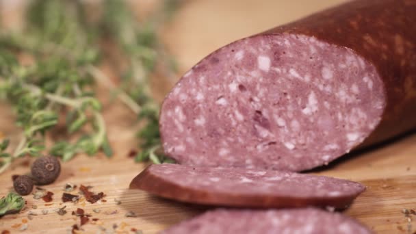 Νόστιμα κρέατα Ντελικατέσεν να τεμαχιστεί με μαχαίρι σε ξύλο κοπής δίπλα από βότανα — Αρχείο Βίντεο