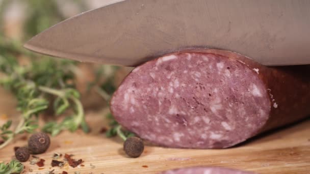 Kielbasa frais tranché au couteau sur une planche à découper à côté d'herbes — Video