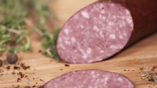 Fresh sausage being cutted with blade on cutting board next to herbs — Stock Video