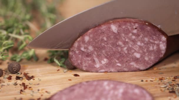 Frischer kielbasa wird mit klinge auf schneidebrett neben kräutern geschnitten — Stockvideo