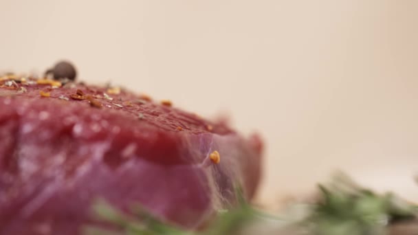 Спеції падають на шматочок сирого свіжого червоного м'яса яловичини на столі — стокове відео
