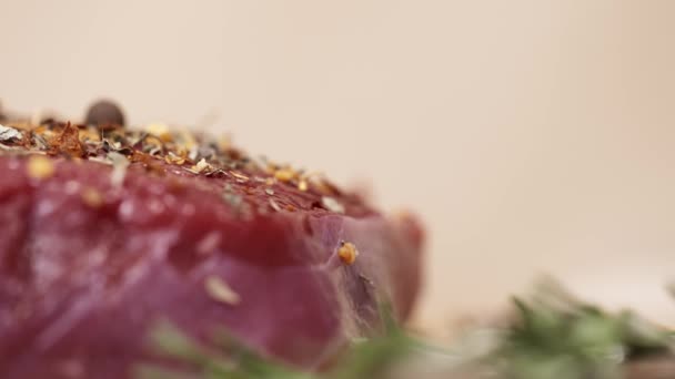 Condimento que cae sobre un trozo de carne de vacuno roja fresca cruda en la mesa — Vídeo de stock